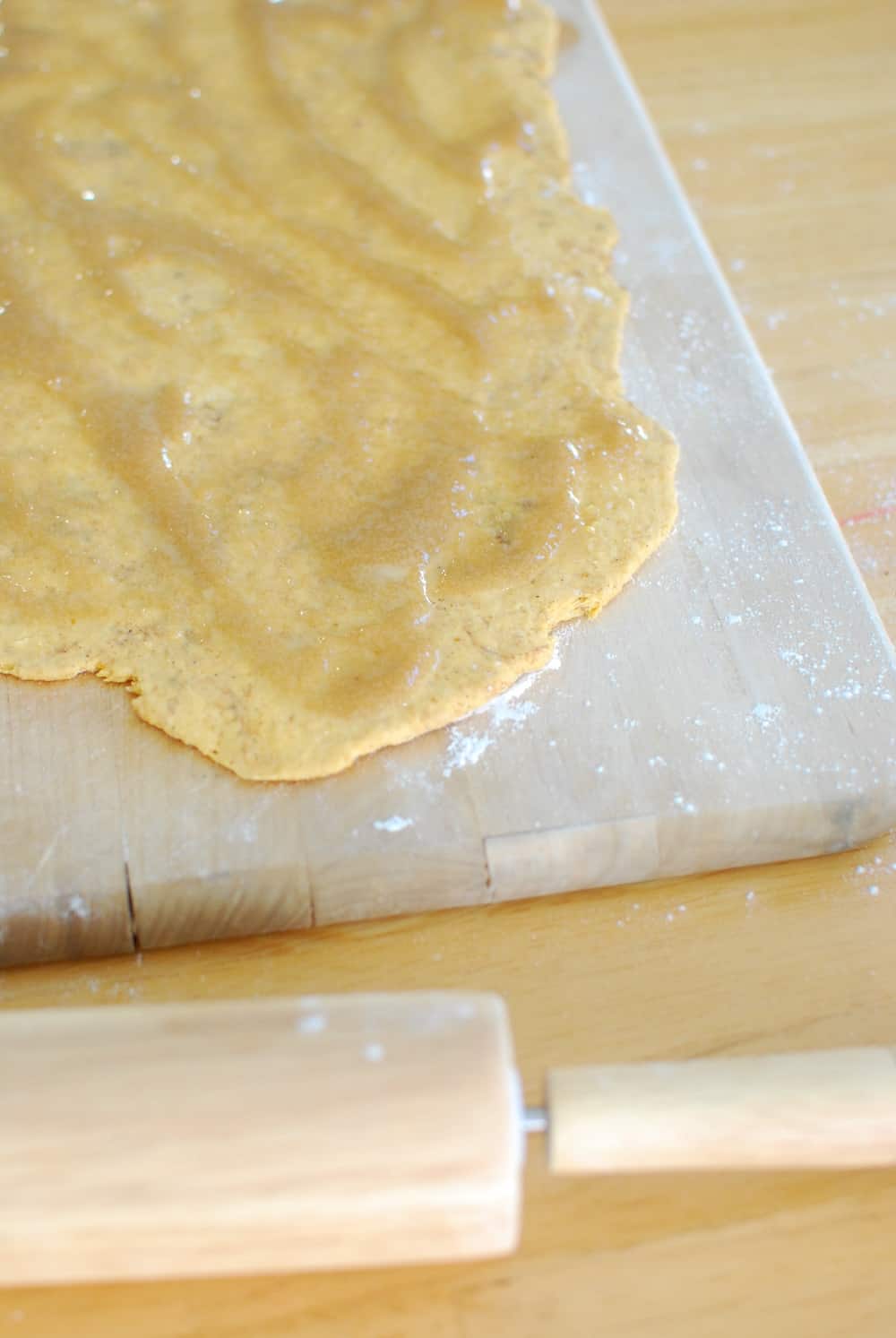 Spreading sugar mixture on the inside of pumpkin cinnamon roll dough