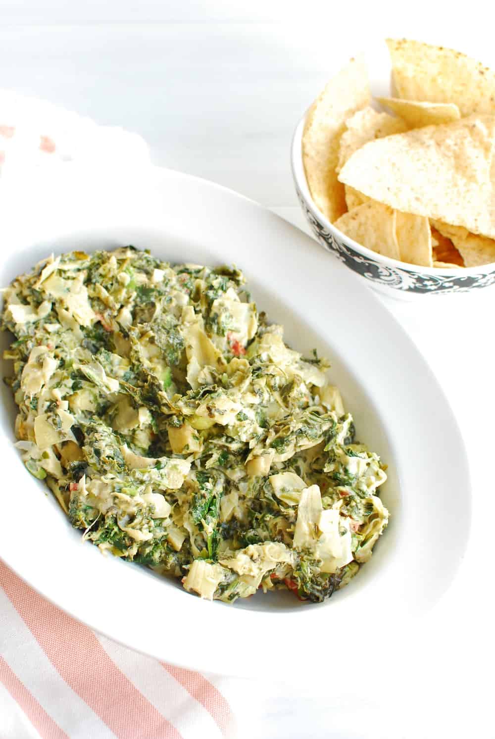 Dairy free spinach artichoke dip in a bowl next to chips