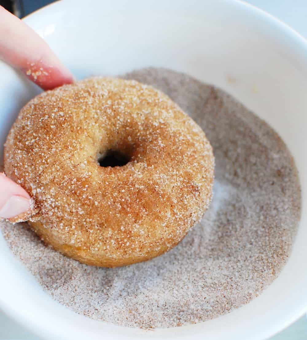 Dipping dairy free donuts in cinnamon sugar mixture