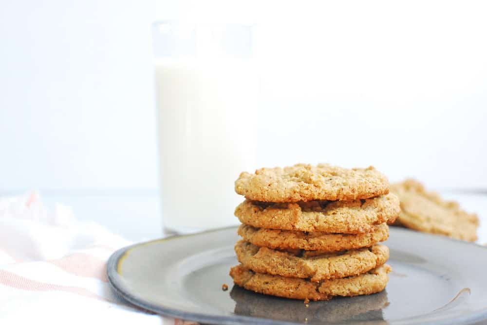 Stack of peanut butter cookies on a plate next to a glass of almond milk