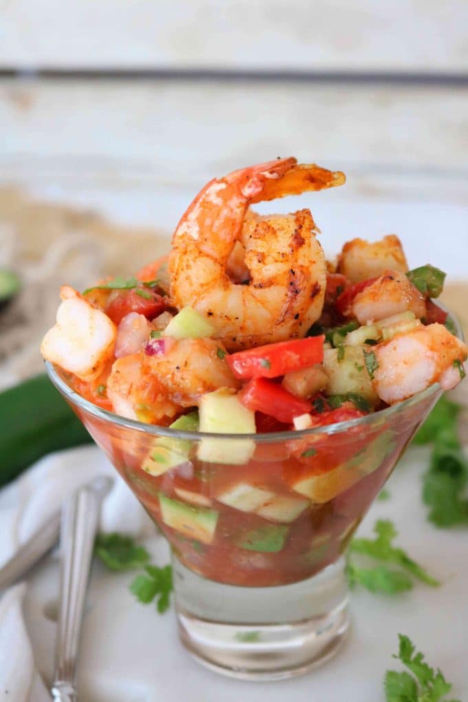 Mexican shrimp Cocktail Appetizer in a glass cup next to green garnish