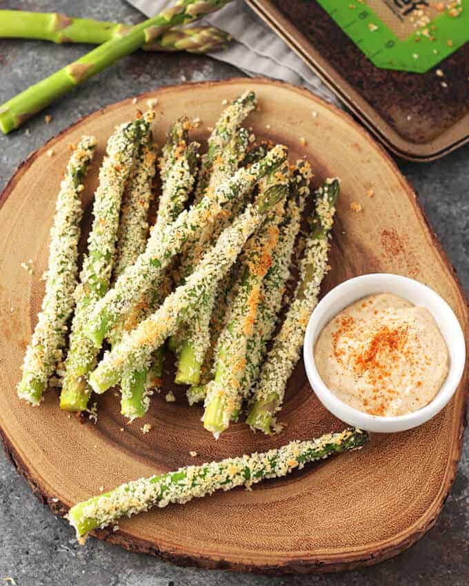 Dairy Free Baked Asparagus Fries on a bamboo platter with aioli sauce in a ramekin