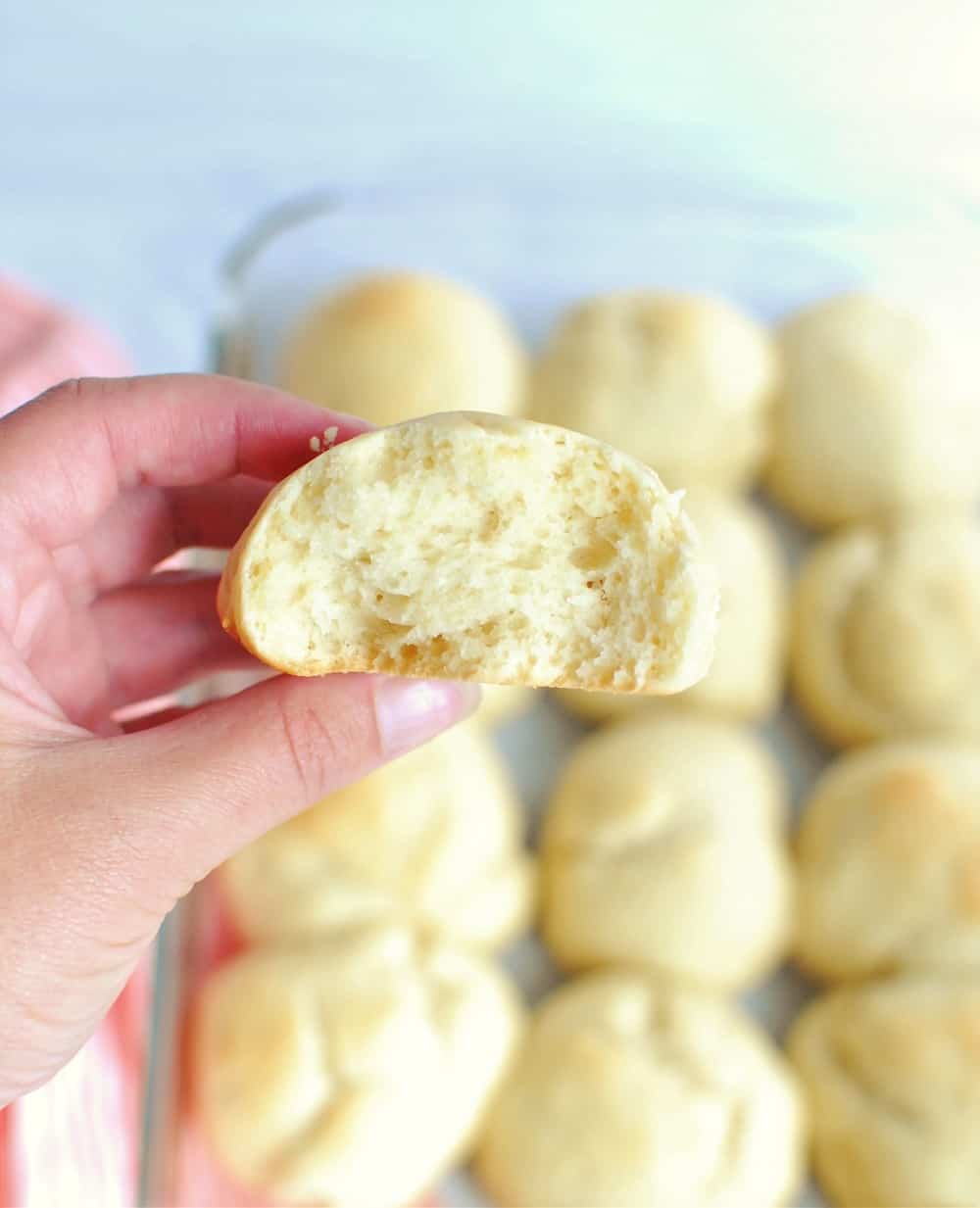 A womans hand holding half of a vegan hawaiian roll