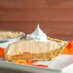 dairy free pumpkin fluff pie on a white plate topped with whipped topping