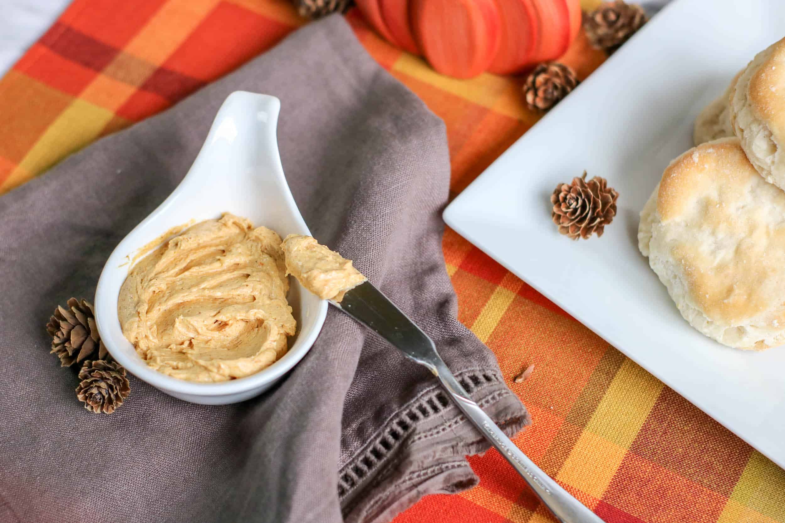 A white bowl full of dairy free whipped honey butter with pumpkin, next to a knife