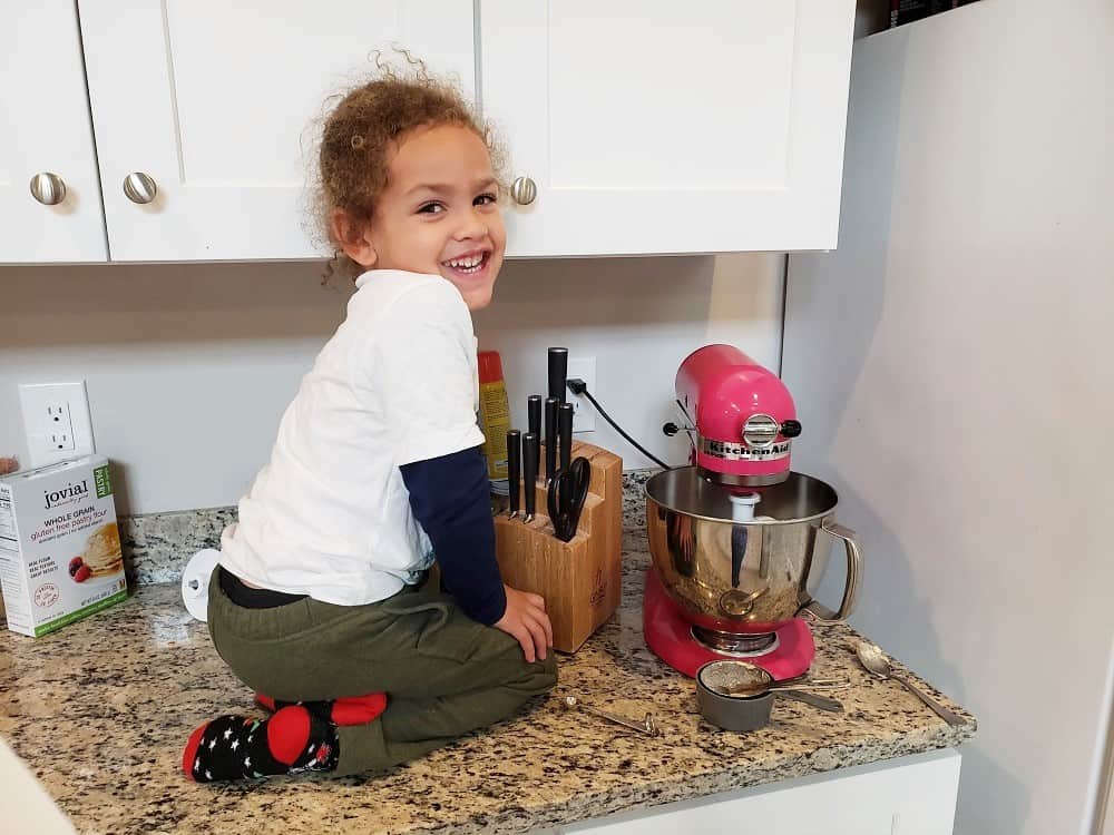 a child sitting next to a kitchenaid mixer