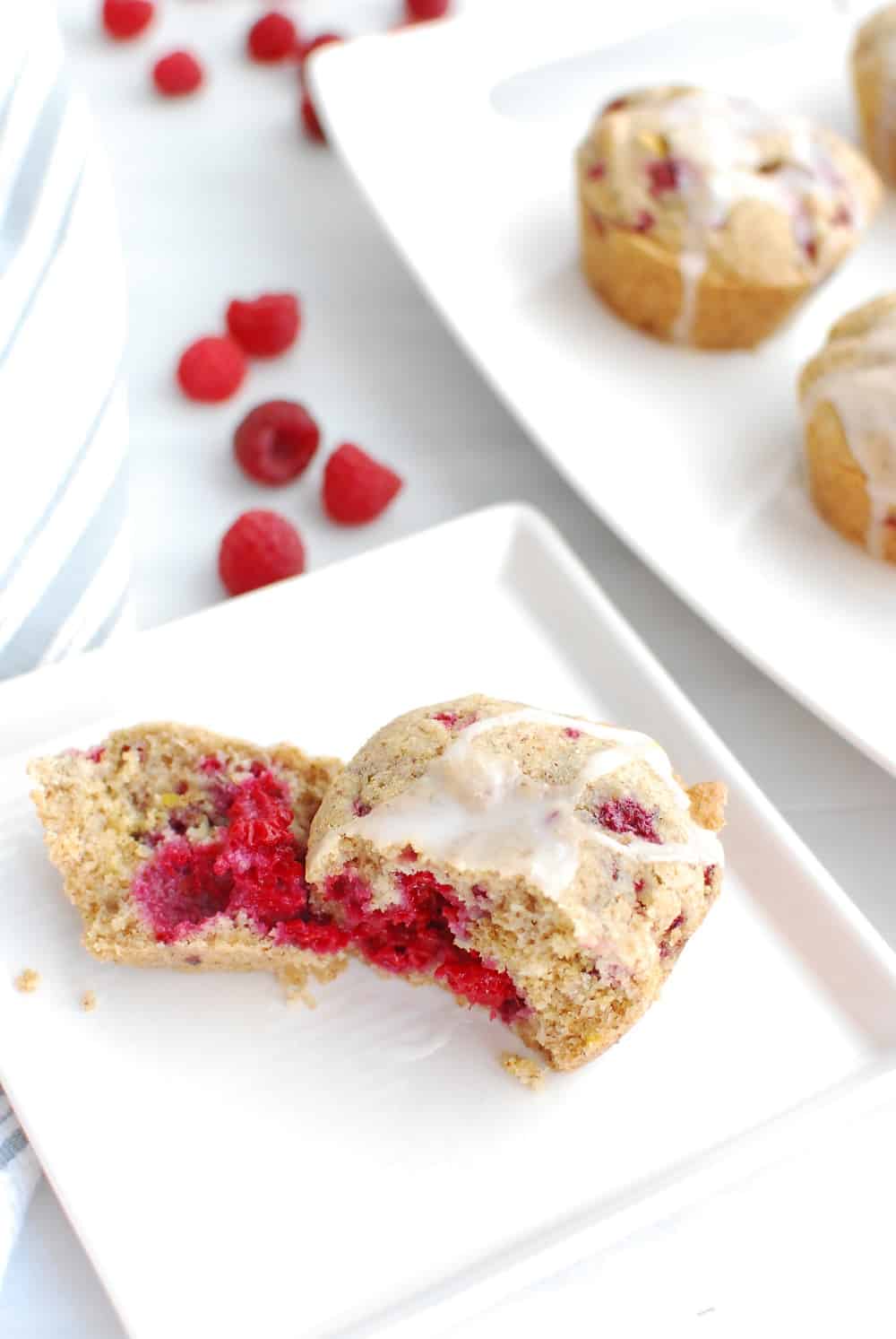 A vegan gluten free raspberry muffin broken in half on a plate