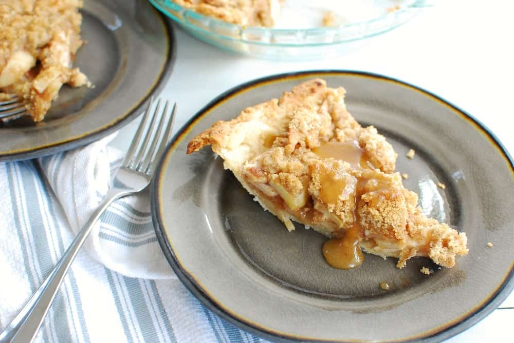 a slice of dairy free apple pie topped with caramel sauce