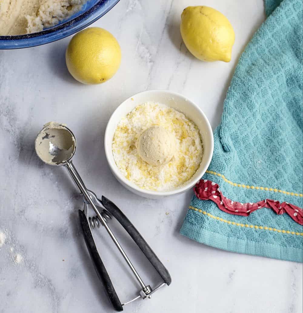 rolling cookie dough in a sugar and lemon zest mixture