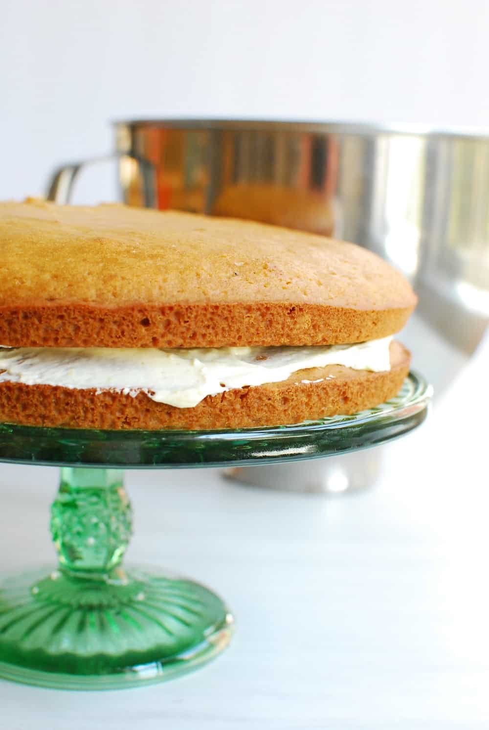 two cakes layered with frosting in the middle on a cake stand