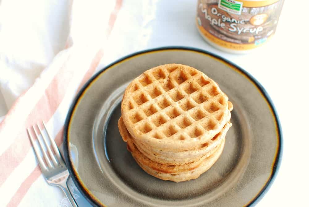 a stack of cinnamon waffles on a plate next to a fork