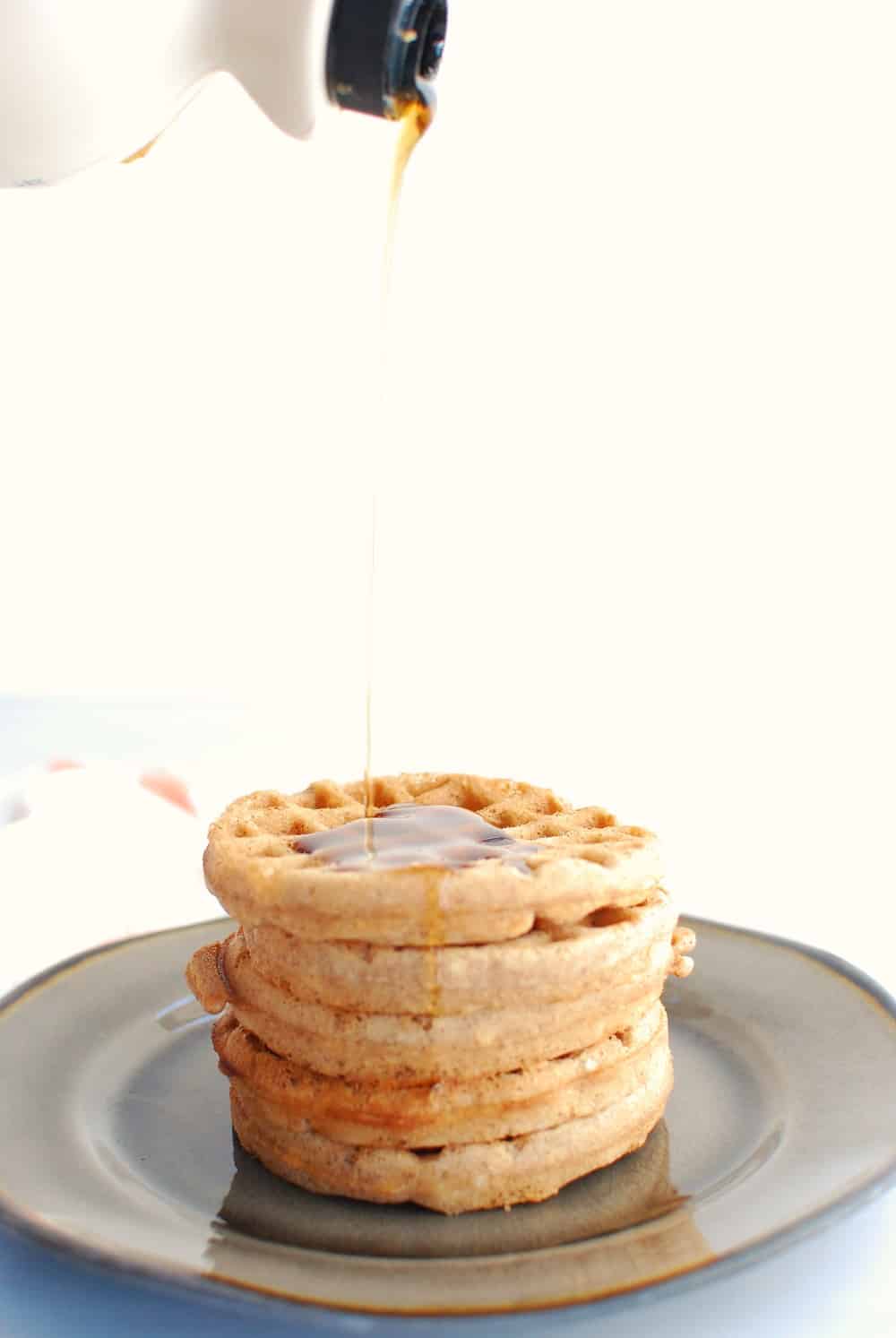 a stack of waffles with syrup being poured on top