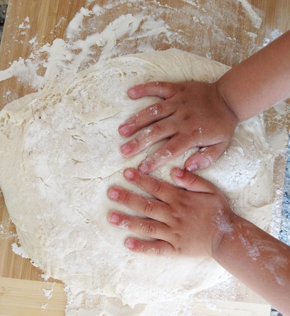 a child kneading dough for bread