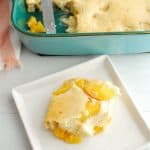 peach pancake casserole on a white plate next to the rest of the casserole dish full of it