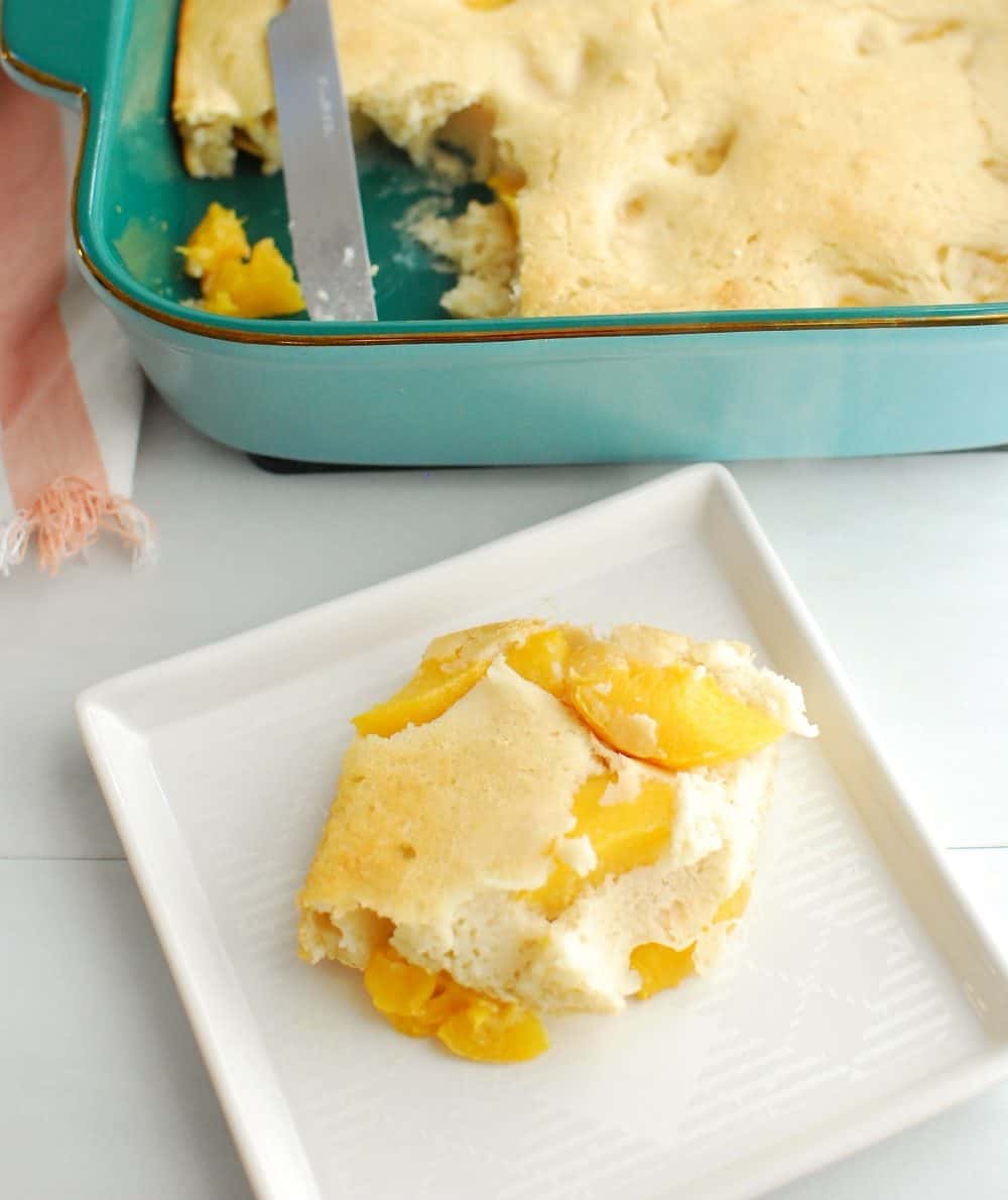 peach pancake casserole on a white plate next to the rest of the casserole dish full of it