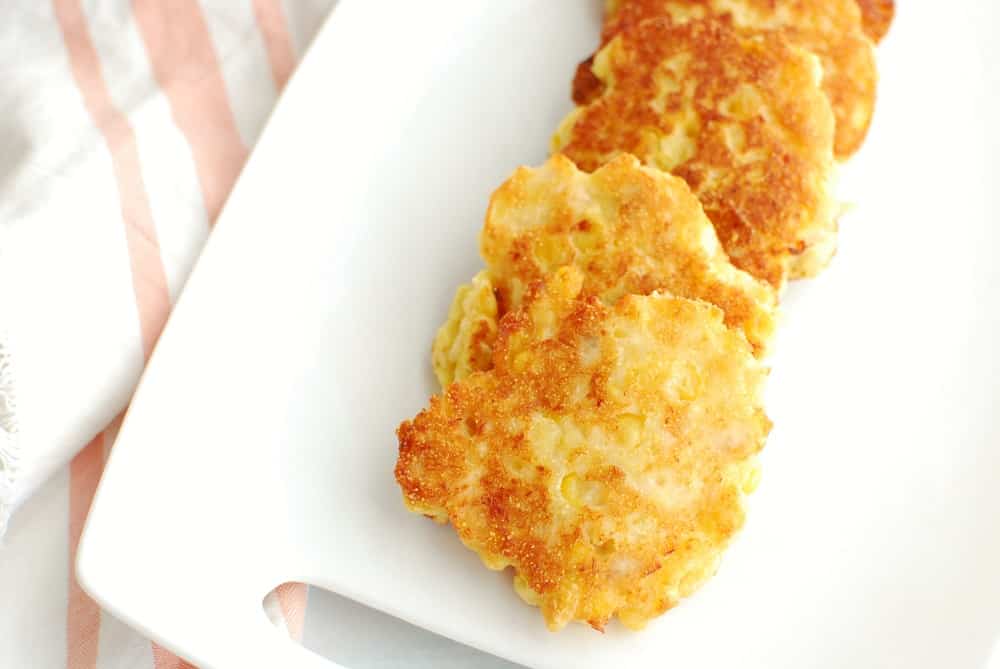 a platter with several salmon corn fritters next to a cloth napkin