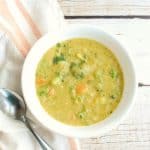 dairy free broccoli soup in a white bowl next to a napkin and spoon