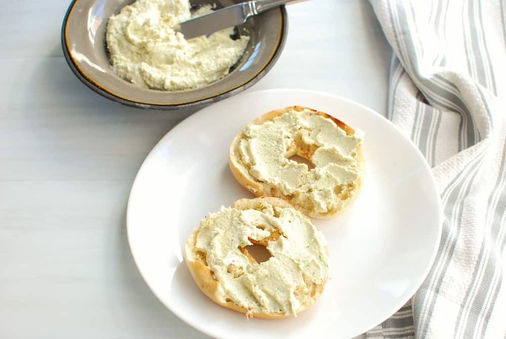 dairy free cream cheese on a bagel on a white plate