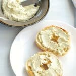 dairy free cream cheese spread on a bagel on a white plate