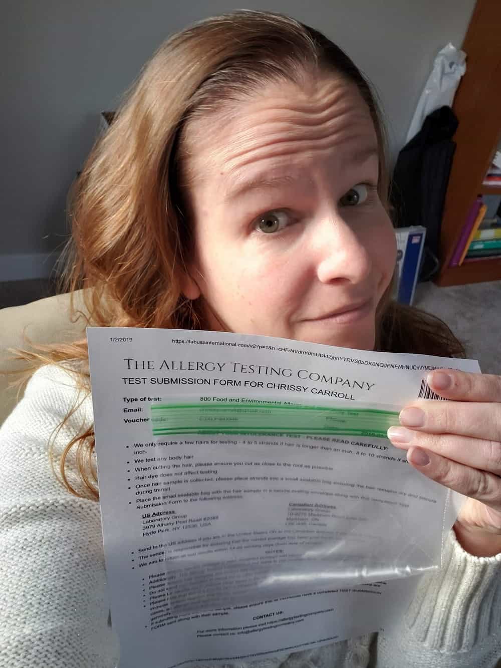 a woman holding up a baggie with strands of hair to be tested