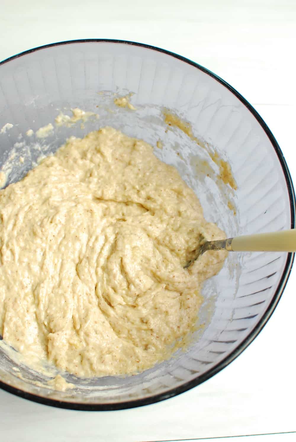 a purple bowl with banana bread batter and a spoon