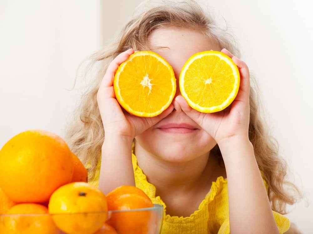 child holding orange slices up in front of her face