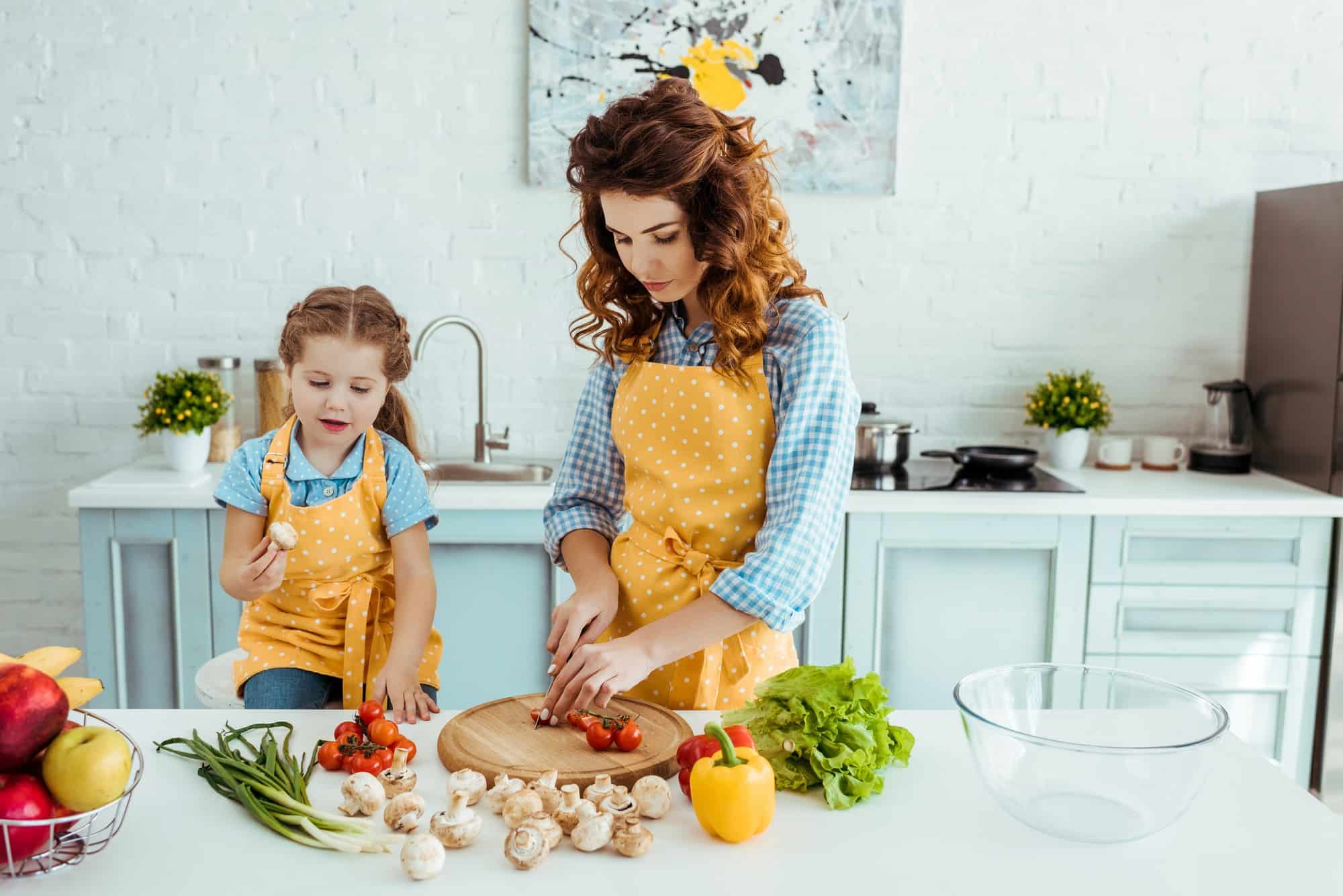 a mother and child preparing vegetables together in the kitchen