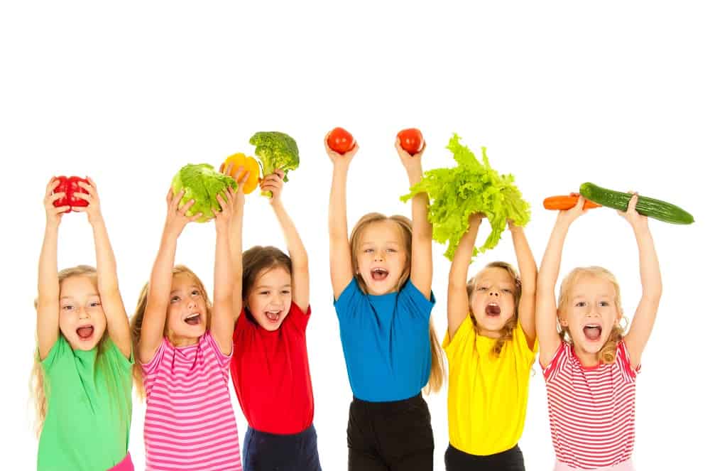 six children holding vegetables in their hands looking excited