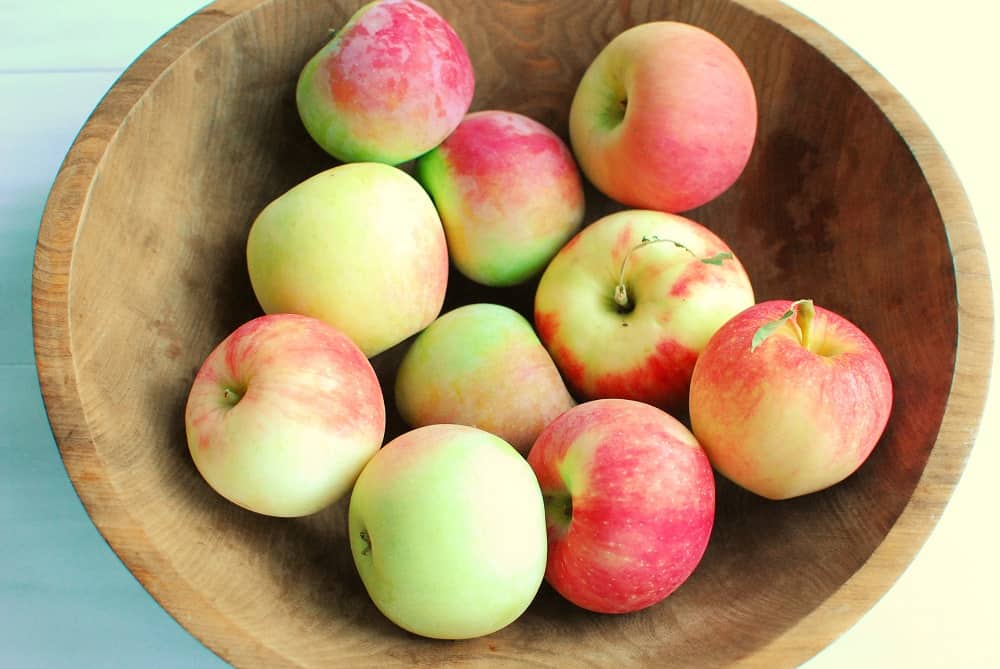 a wooden bowl full of fresh apples