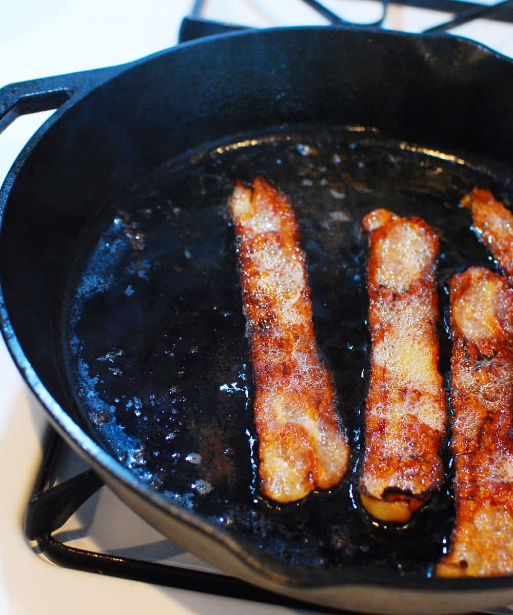 bacon cooking in a cast iron skillet