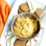 a bowl of dairy free pumpkin dip on a platter with gingersnaps and apples