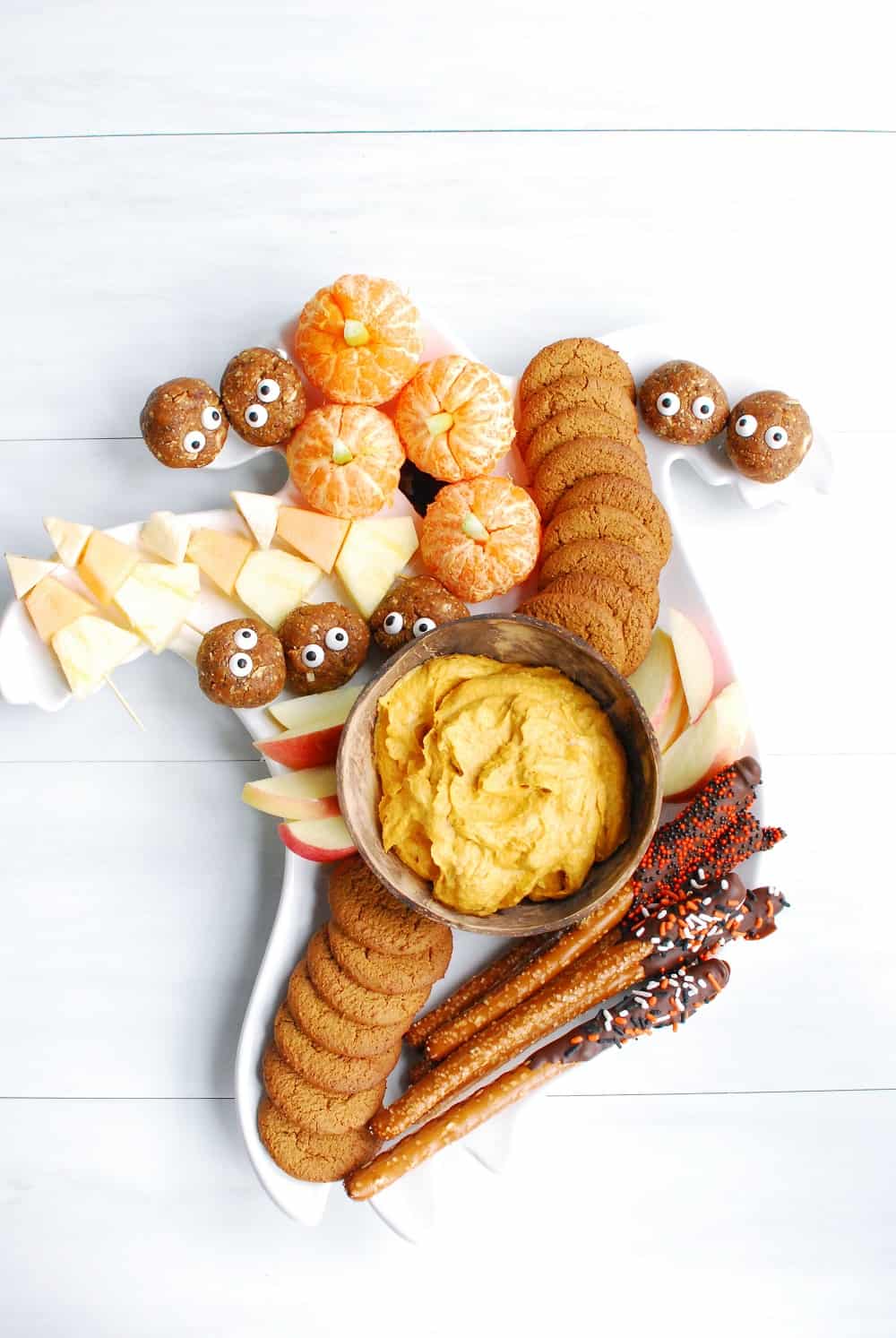 a Halloween charcuterie board filled with five different festive dessert treats, photographed vertically