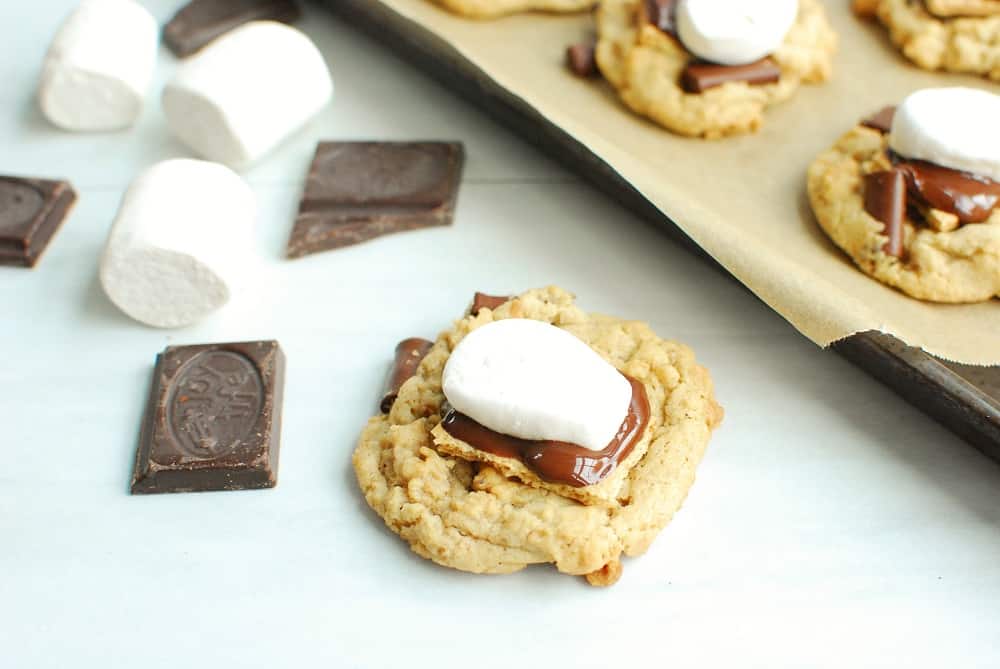 a dairy free smores cookie next to some chocolate and marshmallows