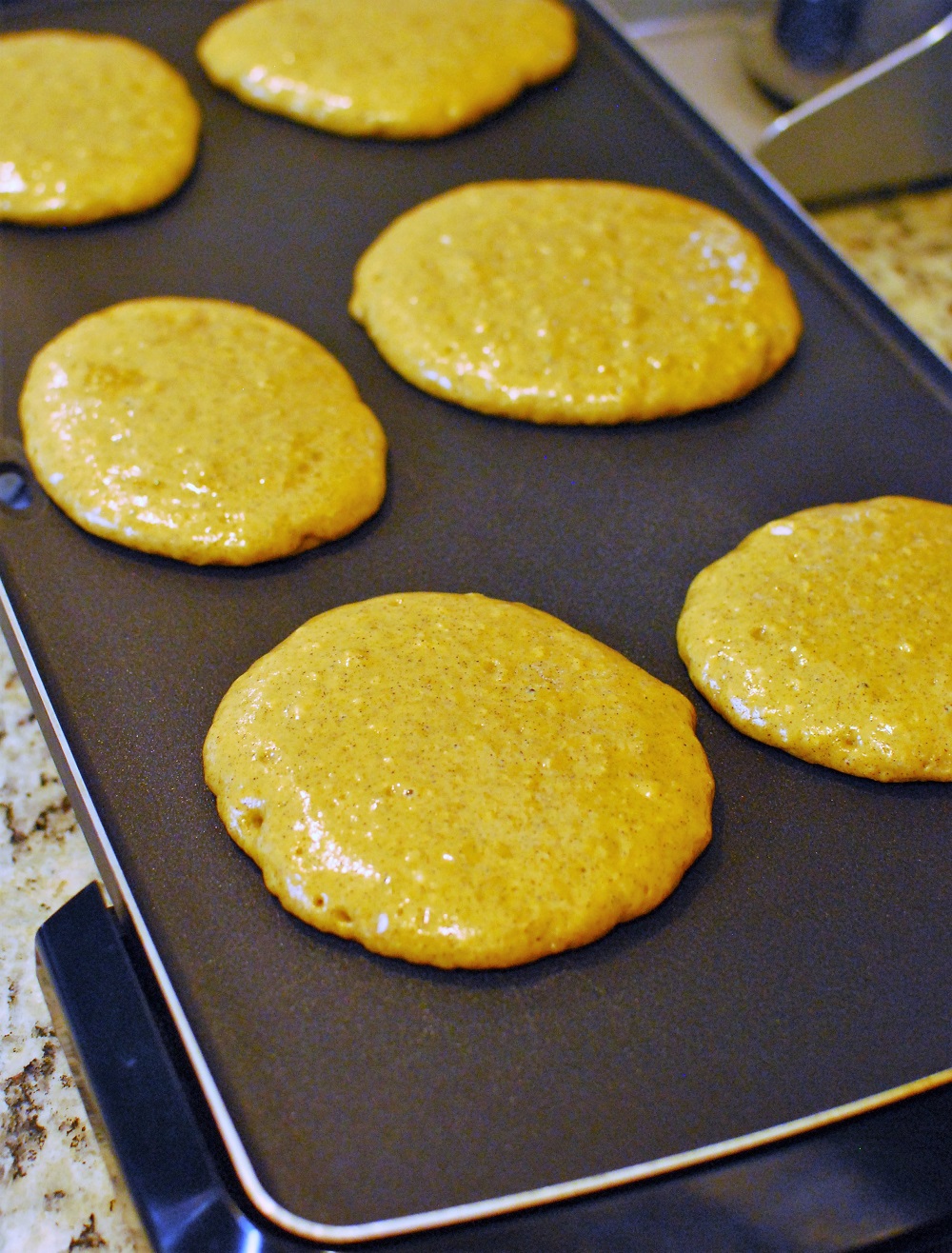 pancakes cooking on a griddle