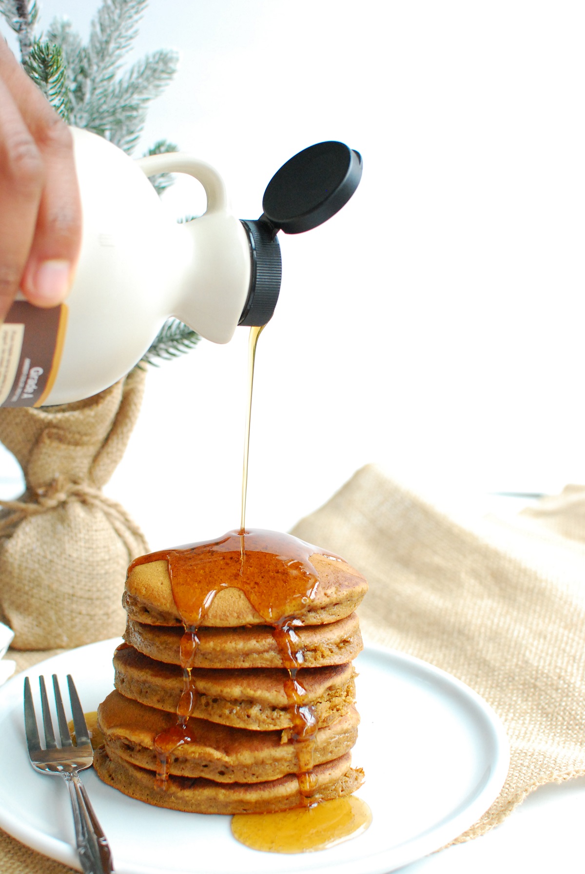 a man pouring syrup onto dairy free gingerbread pancakes