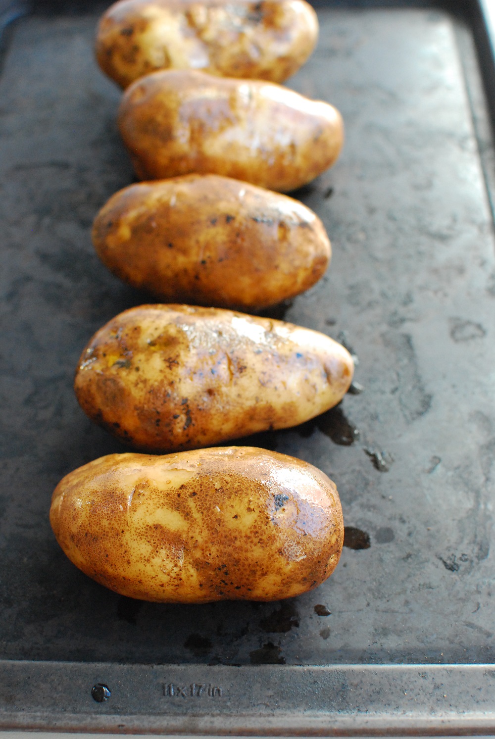 several potatoes on a baking sheet