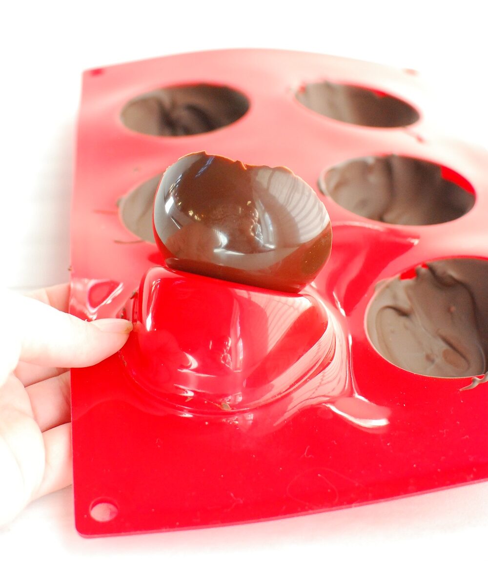 a woman popping chocolate out of a silicone dome mold