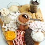 dairy free hot chocolate charcuterie board with mix ins like candy canes, coconut, orange zest, and more