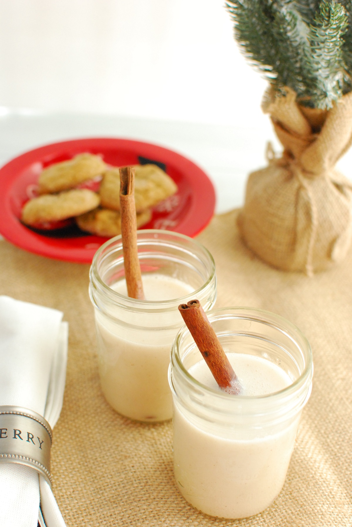 two glasses of vegan coquito garnished with cinnamon sticks