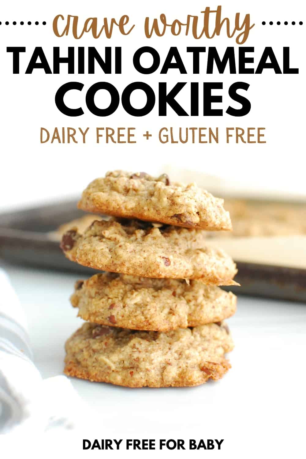 A stack of four tahini oatmeal cookies in front of a baking sheet.