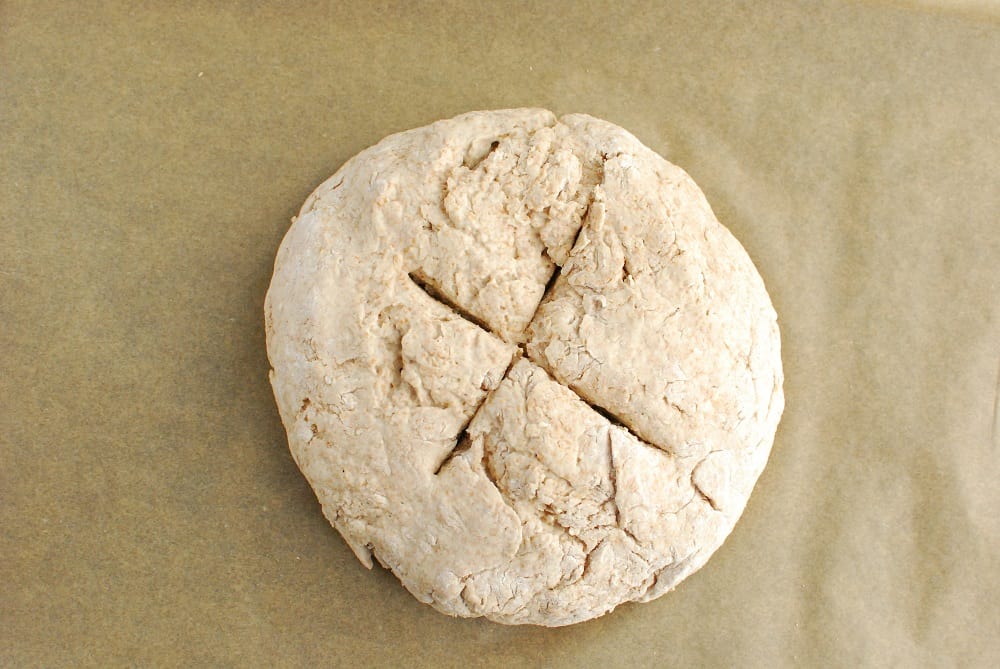 Bread dough shaped into a circle with an X cut in the top.