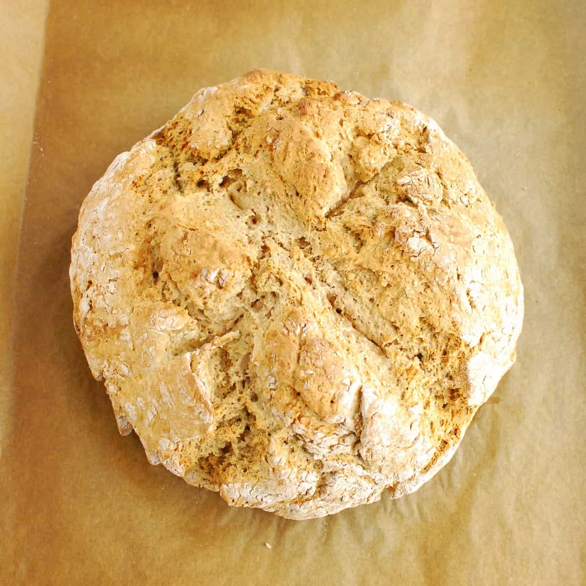 A cooked loaf of vegan Irish soda bread on a baking sheet.