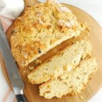 A loaf of sweetened vegan Irish soda bread with raisins with two slices cut from it.