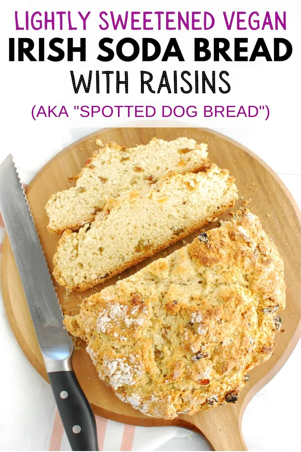 A loaf of vegan Irish soda bread with raisins on a cutting board with two slices cut from it.