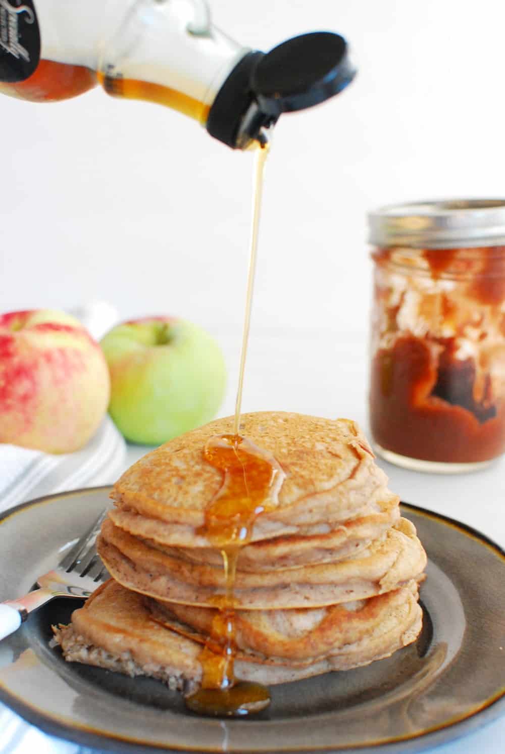 Drizzling pure maple syrup onto a stack of pancakes.