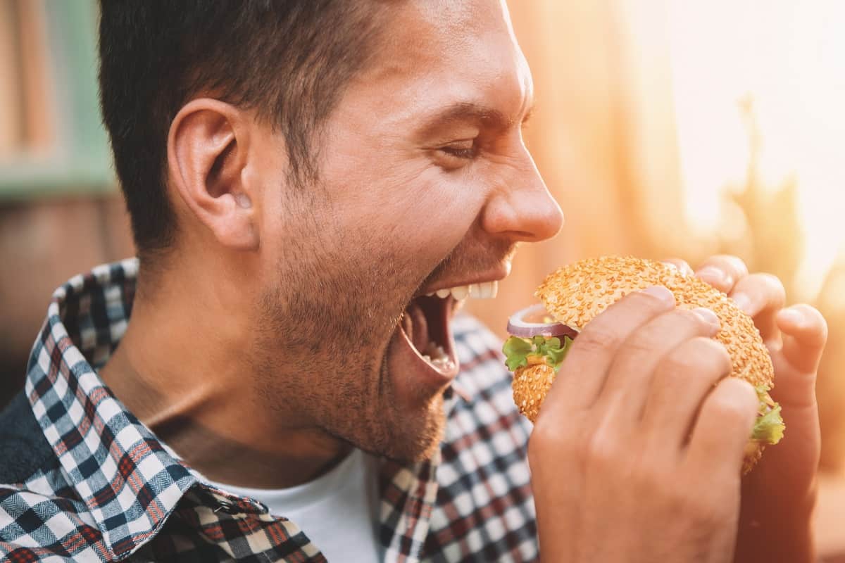 A man eating a dairy free hamburger.