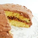 Dairy free yellow cake with chocolate frosting with a slice cut out.