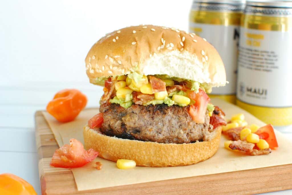 A habanero burger on a piece of parchment paper on a wooden serving dish.