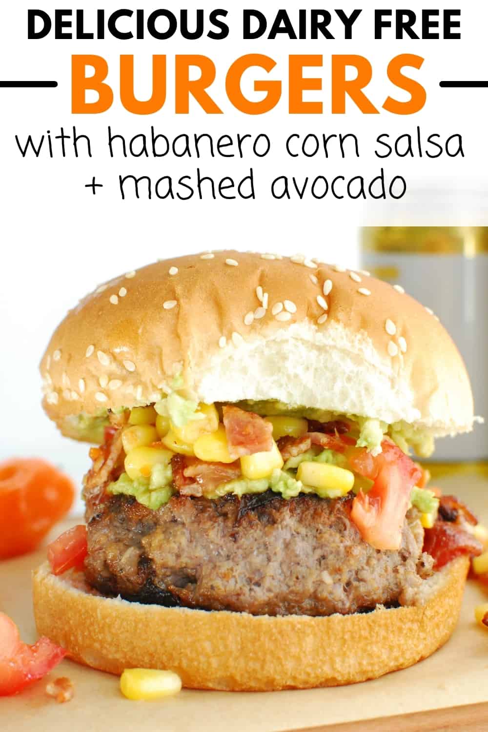 A burger with habanero salsa and mashed avocado on a wooden serving dish.