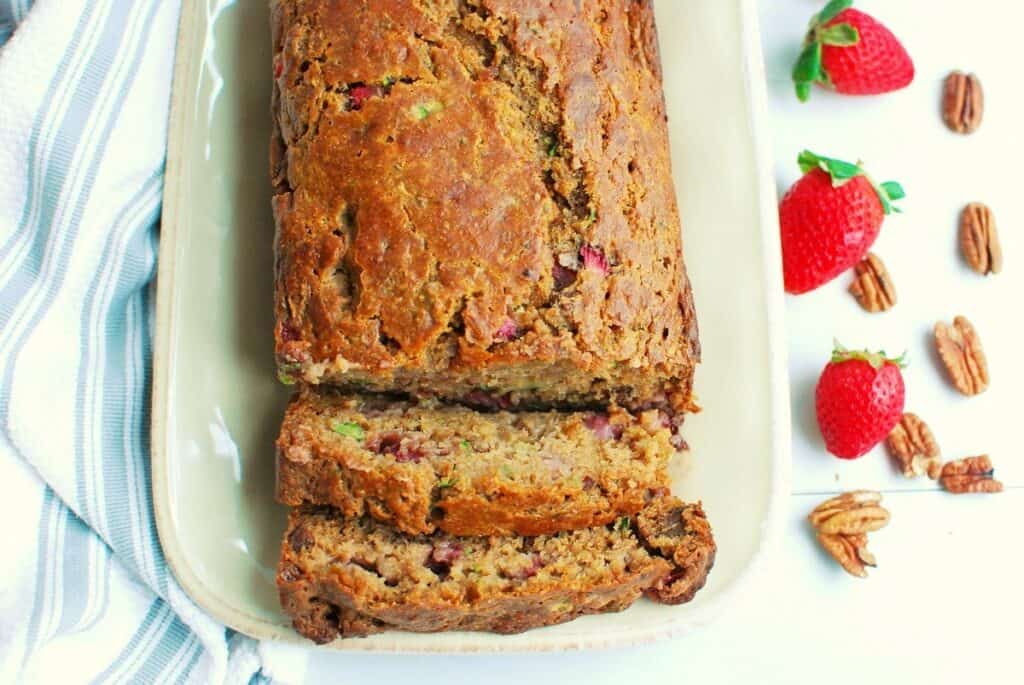 A loaf of zucchini strawberry bread with two slices cut into it.
